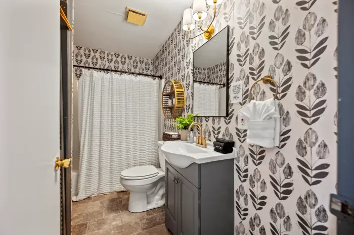 Stylish bath with bold wallpaper, modern vanity & plush linens