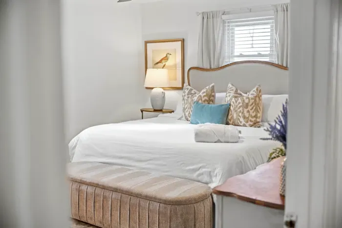 Serene king bedroom with luxe linens, bench seating & soft light.