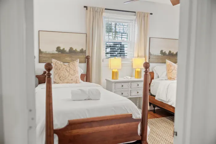 Bright twin room with classic wood beds, fresh linens, and warm lighting