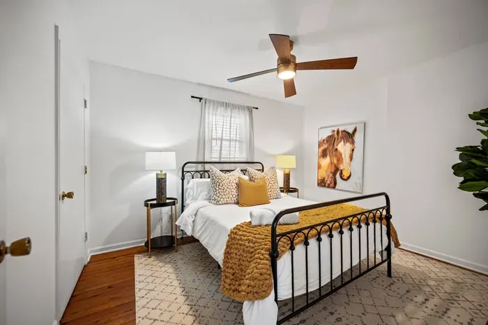 Cozy queen bedroom with ceiling fan, chic decor & warm natural light