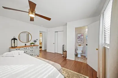 Bright bedroom with ensuite, hardwood floors, and modern ceiling fan