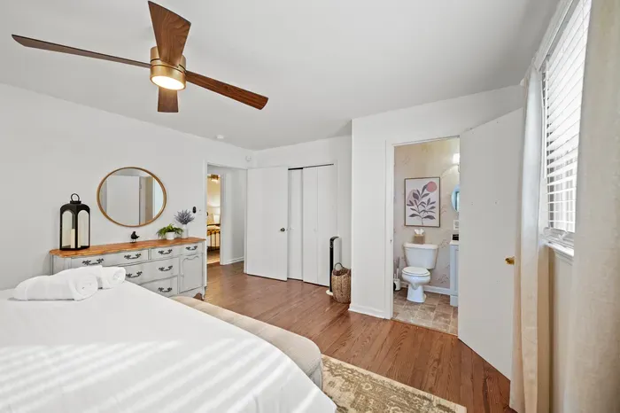 Bright bedroom with ensuite, hardwood floors, and modern ceiling fan