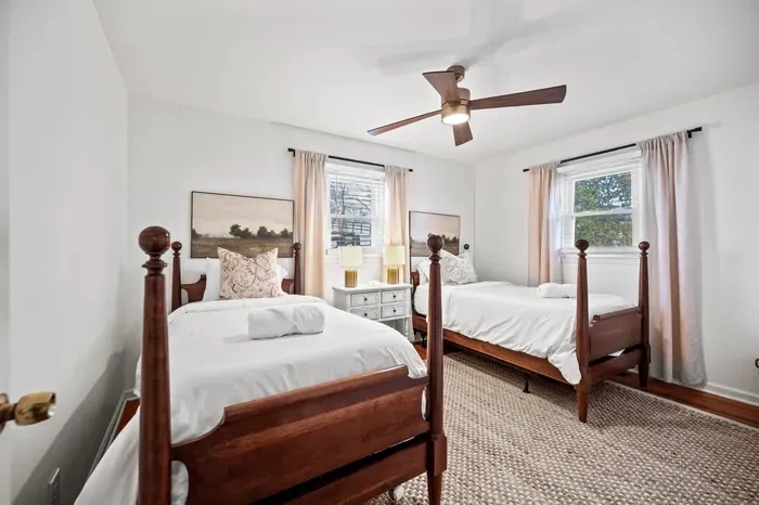 Sunny twin room with classic wood beds, soft linens, and ceiling fan.