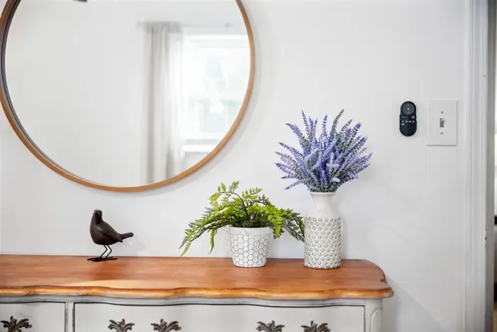 Bright, curated nook with vintage dresser, round mirror, and fresh greenery.