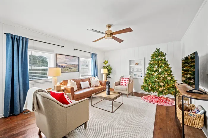 Bright, cozy living room with leather sofa, flat-screen TV & holiday charm