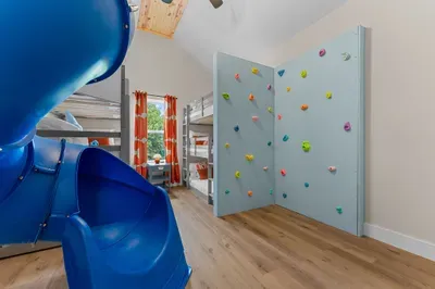 The ultimate kids' room! Six cozy bunk beds, a slide, and a climbing wall make every bedtime an adventure. 🌟