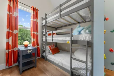 A dream room for kids! With 6 beds, a slide, and a climbing wall, the fun never has to stop. 🧗