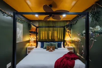 Themed jungle-inspired bedroom with a cozy king bed, warm lighting, and stylish safari decor for a unique and relaxing stay.