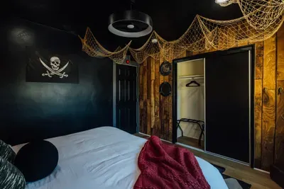 Unique Pirates of the Caribbean–themed bedroom with a striking black accent wall and immersive décor for a fun, adventure-filled stay.