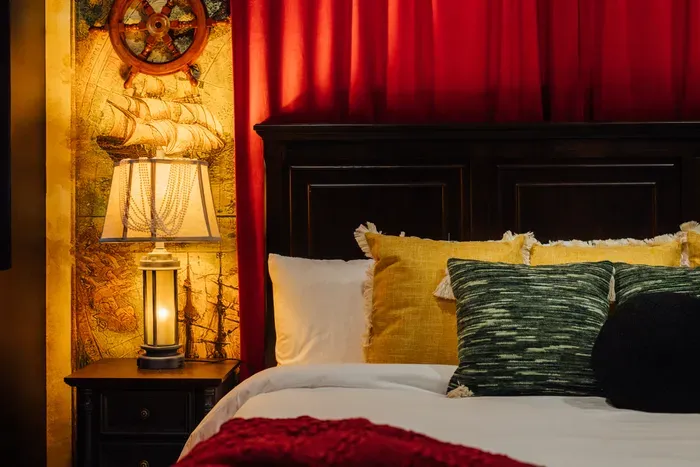 A themed bedroom inspired by Pirates of the Caribbean, showcasing a bold black accent wall and immersive décor that creates a fun, story-like experience.