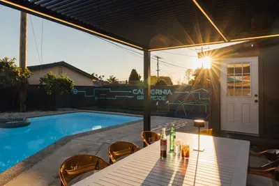 Outdoor covered patio with dining table overlooking the pool, perfect for sunset drinks and casual outdoor meals.