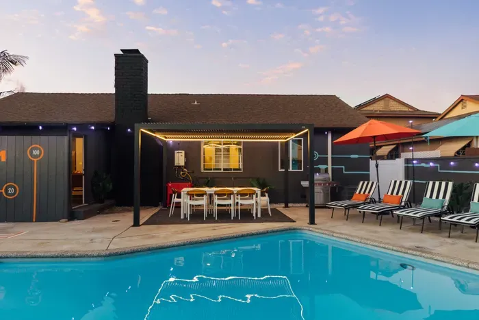 Private backyard pool with lounge chairs, shaded dining pergola, and BBQ grill—perfect for relaxing or entertaining.