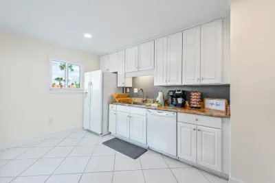 The Seabreeze Villa kitchen is bright and welcoming, featuring crisp white cabinets, marble-inspired countertops, and gold accents. Equipped with modern essentials, including a coffee station to start your mornings right. ☕✨