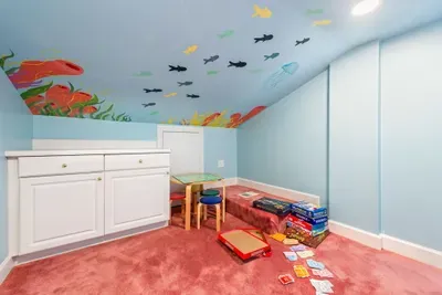 Under the sea adventure awaits! Dive into fun with this playful kids' playroom, featuring a sea life mural on the ceiling, board games, a cozy kids' table & stools. Perfect for endless hours of family fun.
