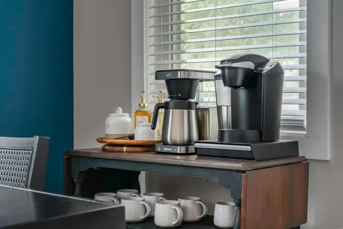 The coffee bar comes equipped with ground coffee, coffee pods, Stevia sugar packets, coffee syrups, a drip coffee maker and Keurig coffee maker