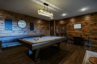 Game room with pool table, two arcade tables, XBOX, shuffleboard, and poker table.