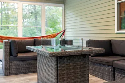Relax year-round in this bright, enclosed porch with comfy seating and a hammock.