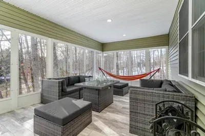 Relax year-round in this bright, enclosed porch with comfy seating and a hammock.