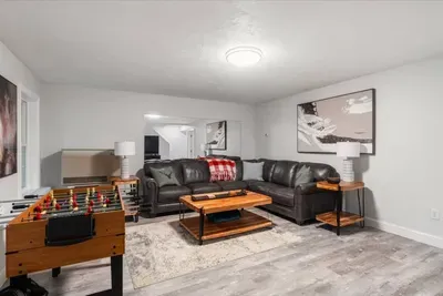 A cozy, spacious living room with plush leather seating, warm wood accents, with windows—perfect for movie nights, après-ski relaxing, game time, or curling up with cocoa after a day on the slopes. A stylish, family-friendly winter hangout.