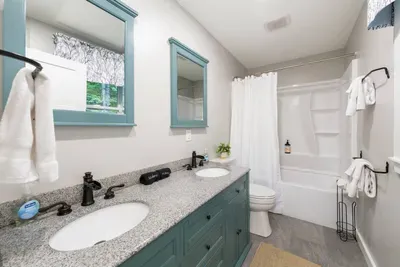 Full bathroom with a double-sink vanity, granite countertop, and shower/tub combo.