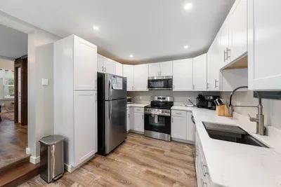 Modern, fully equipped kitchen with stainless steel appliances, sleek white cabinets.