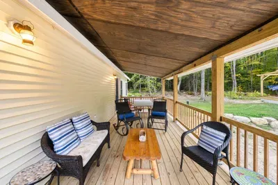 Outdoor spaces featuring a covered patio with cozy seating, a dining area for outdoor meals, and a balcony with forest views.