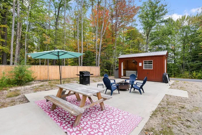 Spacious patio with a hot tub, fire pit, picnic table, and grill.