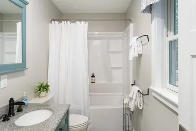 Full bathroom with a double-sink vanity, granite countertop, and shower/tub combo.