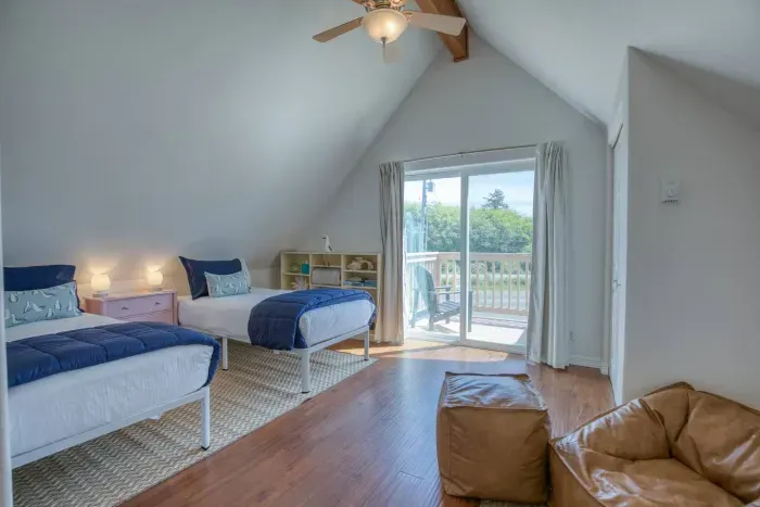 Welcome to the airy upstairs loft bedroom! Features two comfortable twin beds, soaring vaulted ceilings, a cozy bean bag lounge chair, and a sliding glass door that steps right out onto the upper viewing deck at the front.