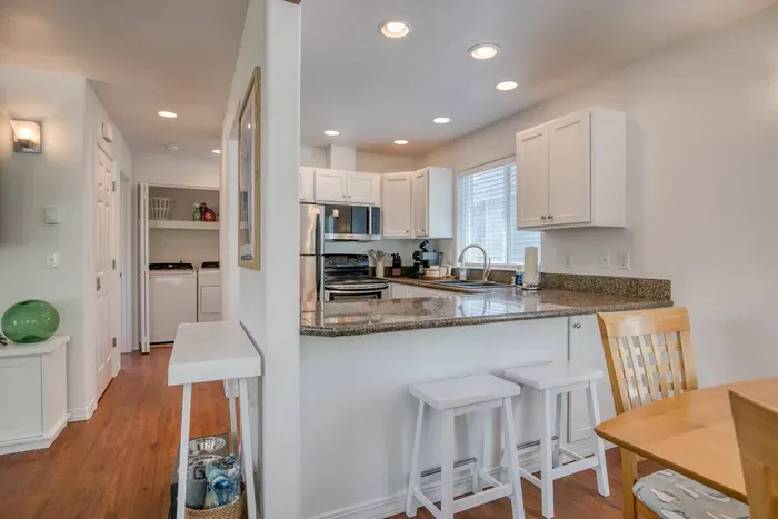 Bright and functional! This hallway connects the main living spaces and features a tucked-away laundry nook with a washer and dryer, providing all the conveniences of home during your stay.