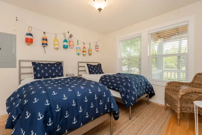 The 'Buoys' bedroom is perfect for kids, featuring twin beds and a dedicated workspace for a productive coastal remote work stay.