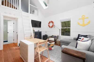 The main living area is a great place to relax after a day at the beach. Cook, watch TV and enjoy time together on the comfy couch. Stairs shown to the second bedroom in the loft - the Captains Quarters. High-Speed Wifi and Smart streaming TV