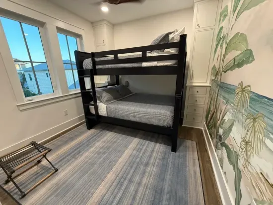 Full-over-full bunk beds with a twin trundle create the perfect sleep space for kids or groups. Enjoy a 50” TV, wall fan, and vibrant jungle mural. Woven wood blackout shades add style and comfort. Built-in cabinets and a full bath just steps away.