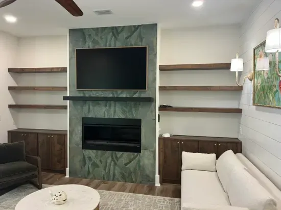 Custom fireplace wall with botanical-inspired tile, floating wood shelves, and Samsung Frame TV creates a sophisticated focal point. Thoughtfully designed built-ins add warmth, storage, and architectural interest.