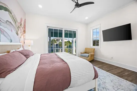 Second primary bedroom with porch access (daytime view shown prior to drapery install) and 55" TV