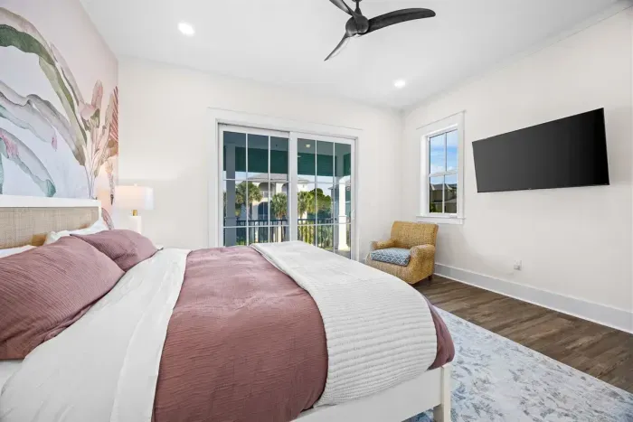 Second primary bedroom with porch access (daytime view shown prior to drapery install) and 55" TV