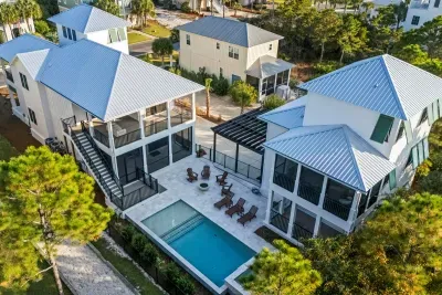 Step back and take in the whole retreat — two coastal homes wrapped around your private pool, fire bowl, and six shaded porches, all yours for the week.