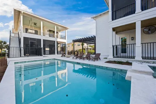 Step outside either home and you're in the same shared courtyard — pool, loungers, and porches on every side, with outdoor stairs bringing the upstairs bedrooms straight down to the pool deck.