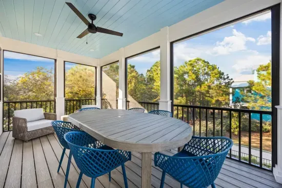 Settle in for a shared meal on the guest house upper porch with six chairs around the table and blue skies through the trees.