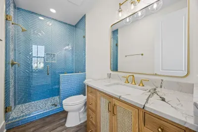 Get ready at the quartzite vanity, then step into the guest house's own walk-in shower — the perfect ensuite for the spacious, private primary bedroom.