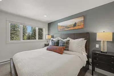 Cozy king bedroom with forest views and warm mountain-lodge style