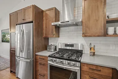 Modern chef’s kitchen with gas range, stainless appliances, and warm wood cabinets