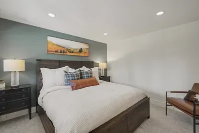 Cozy king bedroom with stylish accent wall and plush, inviting bedding