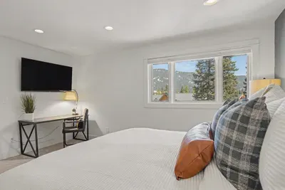 Bright bedroom with mountain views, workspace, and wall-mounted TV