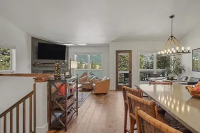 Bright mountain-view living space with fireplace, dining area, and deck access