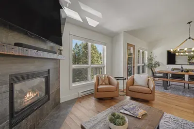 Cozy fireside living room with forest views and stylish open dining