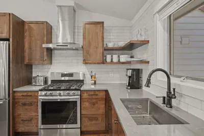 Bright modern kitchen with gas range, open shelving, and large sink
