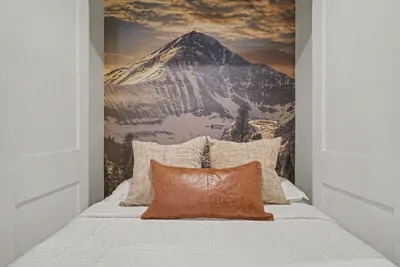 Cozy bed nook with dramatic mountain mural and warm, inviting style