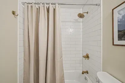 Bright tiled tub-shower with stylish brass fixtures and a clean, modern look