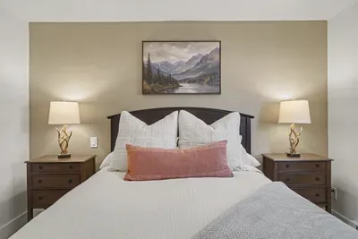 Cozy bedroom with warm lighting, plush bedding, and rustic mountain charm